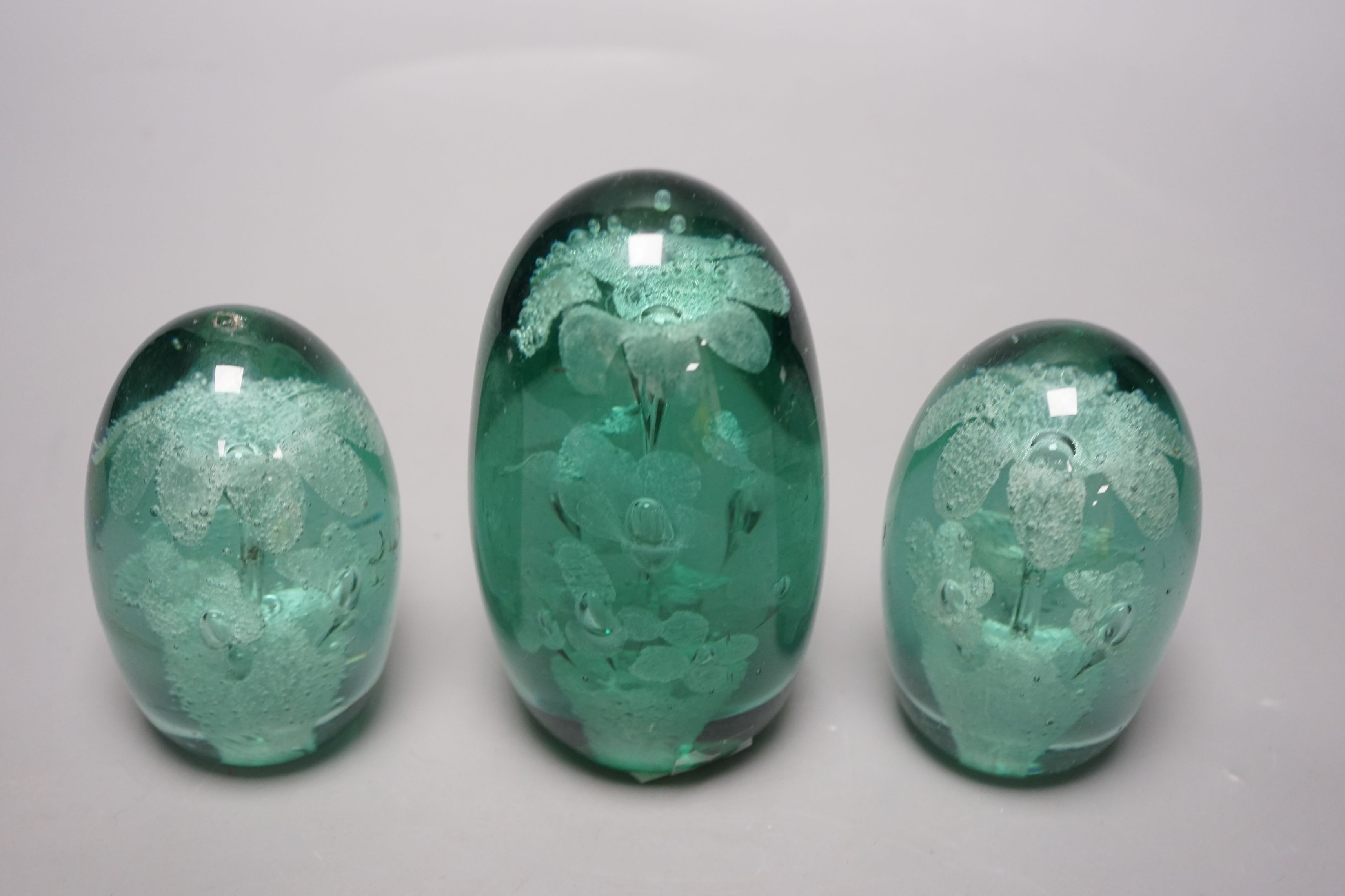 Three green glass dump paperweights, tallest 14cms high